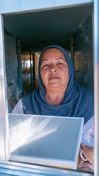 Latin American woman in a navy blue knitted headscarf holding a medical prosthesis box, resolute and direct for survivorship and health covers