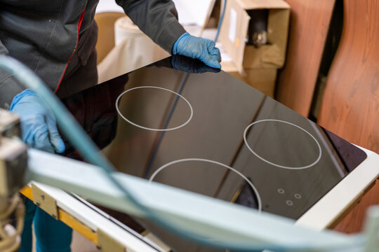 Worker installing black glass induction cooktop in kitchen setting