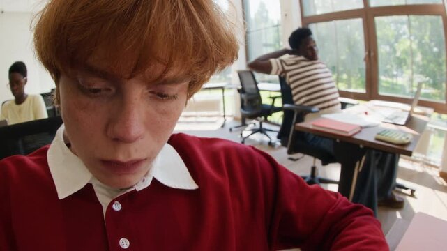 Caucasian young adult male drawing pie chart on paper, camera tilting up to show his focused face in office. Video suitable for corporate training, startup marketing, and business presentations