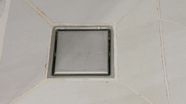 Stainless steel square floor drain in bathroom.