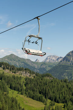 Col dei Baldi, Italy. Empty chairlift above alpine forest with panoramic Dolomite mountains