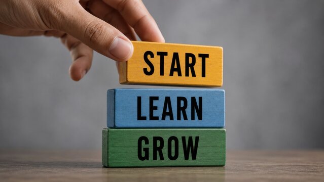 Hand placing yellow block on top of blue and green blocks labeled start learn grow for development.