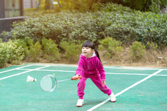 Asian little girl playing badminton outdoors, active child exercising in park, healthy lifestyle and childhood activity