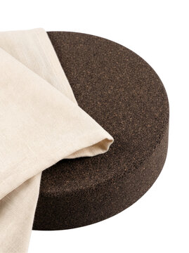 Dark cork disc with folded white fabric on white background-(Cakram gabus gelap dengan kain putih terlipat di latar belakang putih)