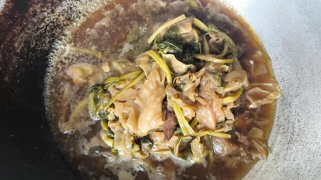 Top-down view of traditional Thai-Chinese vegetable stew (Tom Jab Chai) simmering in a large wok. 