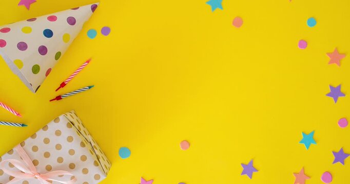 Birthday flat lay with a party hat, festive candles, a gift on a yellow background with a place for a text. Stop motion animation