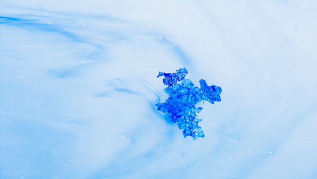 Blue crystal dissolving in abstract liquid creating fluid shapes
