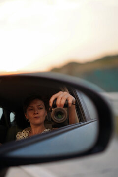 Woman taking a selfie in a car side mirror