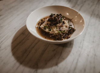 Gourmet bowl of grits with microgreens on marble © Cavan