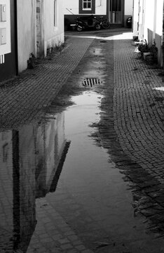 Building reflection in a puddle on a wet cobblestone alley