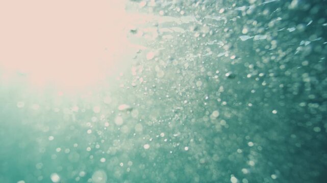 Sunlit air bubbles drift through turquoise water beneath a softly illuminated surface underwater, abstract peaceful underwater backdrop