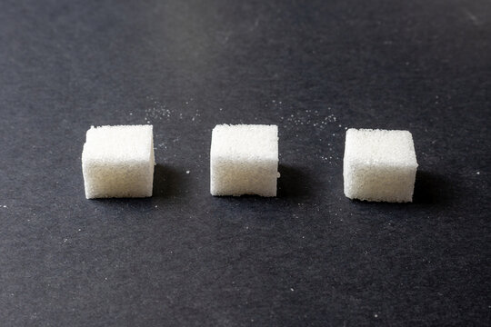 Three sugar cubes on dark background