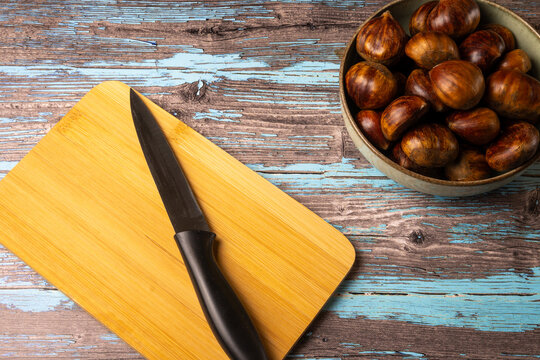 Chestnuts with kitchen knife on wooden cutting board