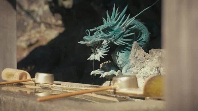 An ornate dragon statue forms the water spout of a chōzuya purification basin at Hansobo Shrine in Kamakura, part of the ritual hand-washing tradition practiced before entering Japanese temples.