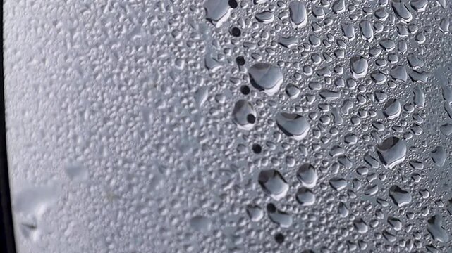 Video close up of water droplets on car side mirror.