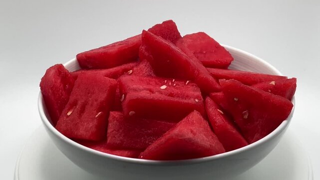 Fresh red watermelon slices in a white bowl isolated on white background.