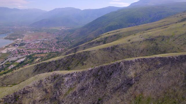 Rocky mountain ridge above Mostar, Bosnia and Herzegovina with valley settlement below, aerial landscape backdrop reveals textured escarpment