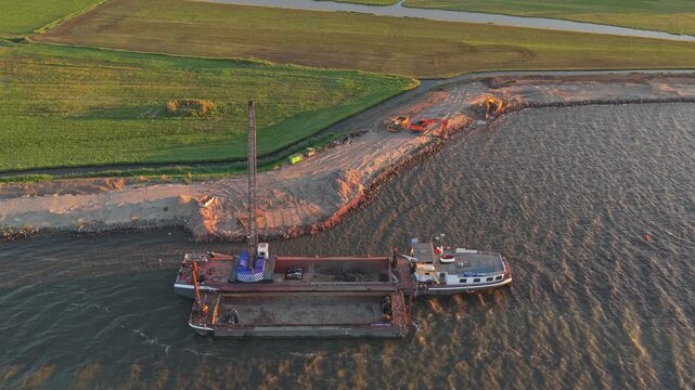 High angle aerial view of a dredging ship with a crane strengthening a dike along the coast, a crucial part of dutch water management