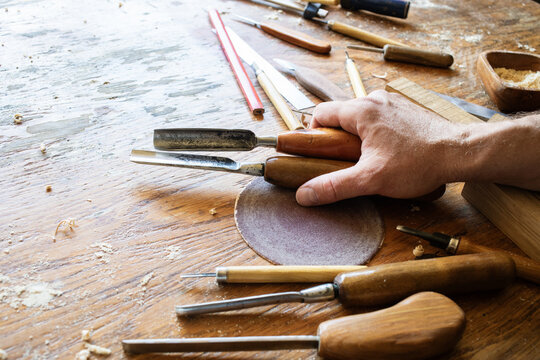 Carpenter hand with handmade wood carving tools at workbench. Joinery, carpentry, wooden craftsmanship and handwork background.