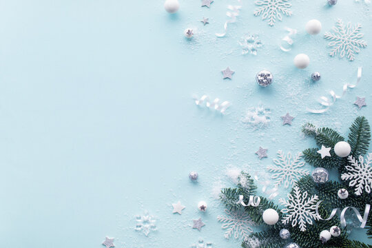 Festive Christmas and New Year holiday snowy composition with spruce branches, white snowflakes, silver baubles and winter decoration top view.