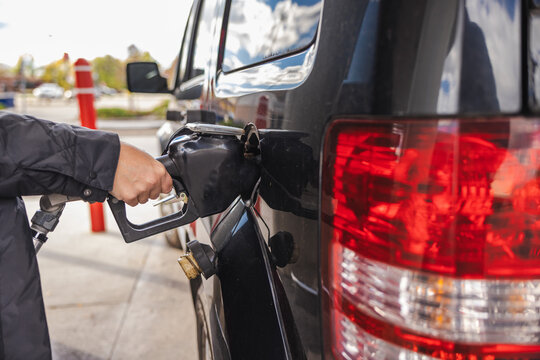 Hand Refueling Black SUV at Gas Station