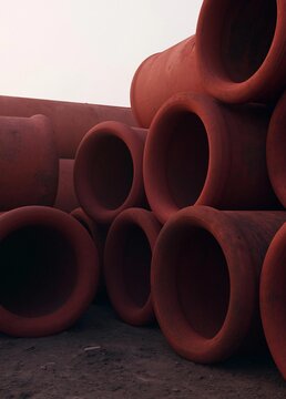 Group of red clay pipes stacked on top of each other. the pipes are cylindrical in shape and appear to be made of a similar material, possibly clay or terracotta.