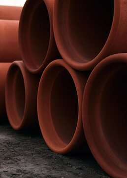 Group of red clay pipes stacked on top of each other. the pipes are cylindrical in shape and appear to be made of a similar material, possibly clay or terracotta.