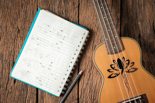 Vintage Ukulele, Pencil, and Written in a child's handwriting. on Rustic Wooden Background.