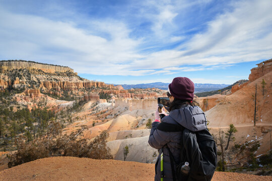 A visitor taking a photo of the tall, thin spires of rock called hoodoos at Bryce Canyon National Park. Utah. USA.