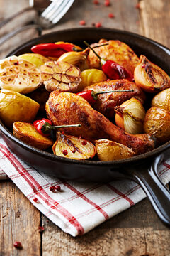 Roasted chicken wings with baked potatoes and peppers in a frying pan. 