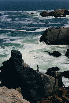 Lone figure walks along a dramatic rocky coast