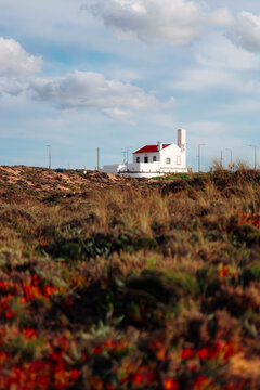 A white house with a red roof on a coastal dune