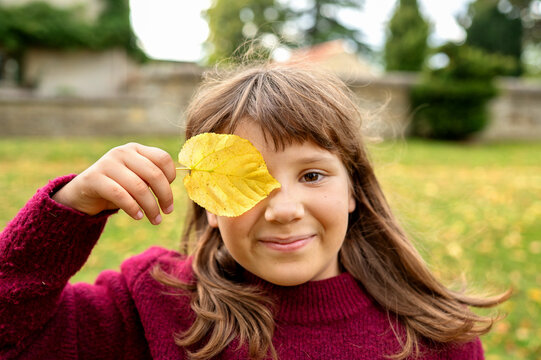 Happy girl covering her eye with a yellow leaf
