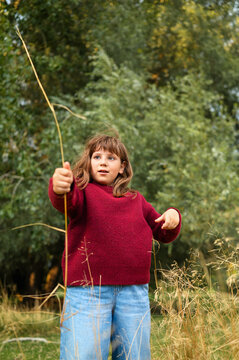 Young girl exploring nature while holding a long grass stem