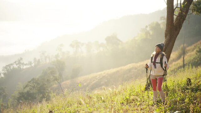 Asian mature woman travel nature hiking on mountain above cloudscape at sunrise. Female traveler with backpack enjoy outdoor active lifestyle , aging gracefully healthy wellness on holiday vacation