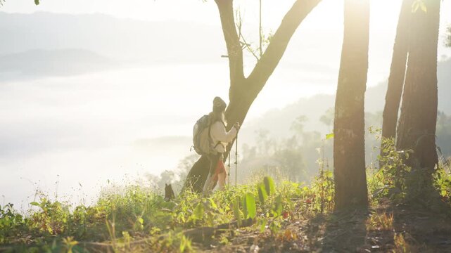 Asian mature woman travel nature hiking on mountain above cloudscape at sunrise. Female traveler with backpack enjoy outdoor adventure, aging gracefully healthy active lifestyle on holiday vacation