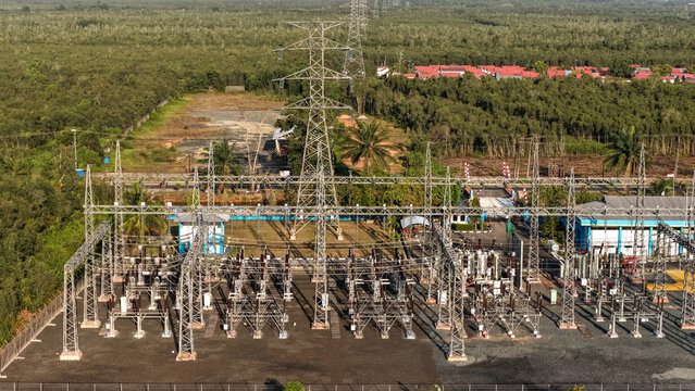 Aerial view of an electrical power grid facility surrounded by lush green tropical trees during day
