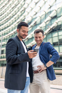 Technology startup founders collaborating with smartphone outside office building
