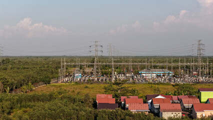 Obraz premium Electrical grid infrastructure set near a suburban area with green trees and a clear daytime sky