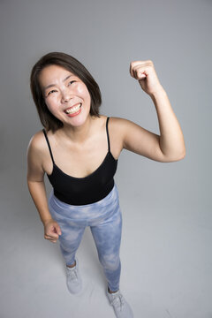 笑顔で元気にガッツポーズ、フィットネス運動を楽しむ40代の女性、更年期に健康とダイエットを意識したトレーニング俯瞰