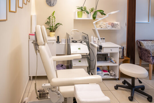Clean empty pedicure treatment room with chair and white equipment shelves