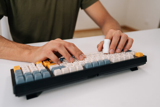 Close-up of human hands typing on custom mechanical keyboard with finger splint, illustrating work-related injury, repetitive strain, recovery, r ergonomic challenges in modern office setup.