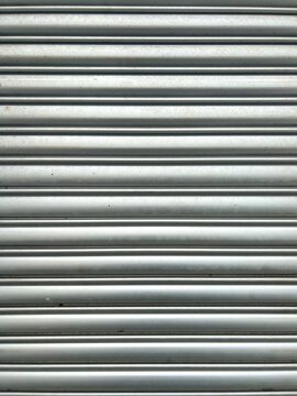 Front view of a closed silver metallic roller shutter door with a clean horizontal stripe pattern.