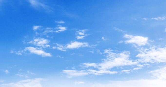 Clear blue sky with soft white clouds drifting