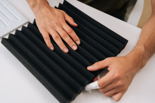 Top view of man checking soundproof foam panel, doing quality check before installing acoustic insulation, preparing for diy project to improve audio quality and reduce noise for home recording.