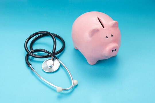 Top View of Piggy Bank Beside Medical Stethoscope on Blue Background