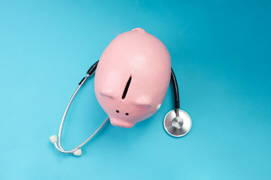 Top View of Medical Stethoscope with Piggy Bank on Blue Background