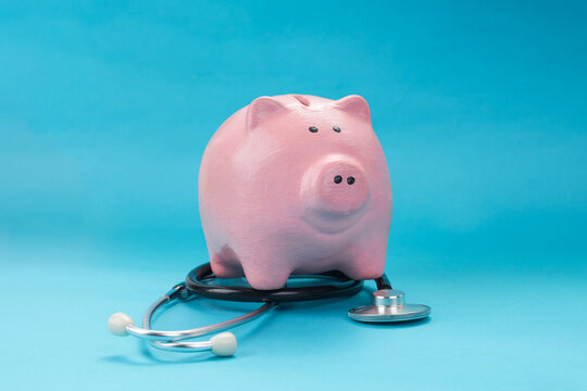 Closeup of Piggy Bank on Medical Stethoscope Against Blue Background