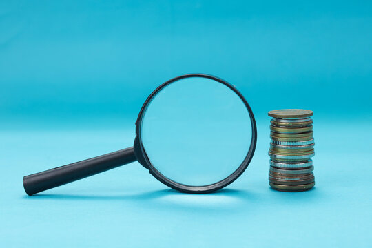Closeup of Inspection Tool Next to Accumulated Currency Against Blue Background