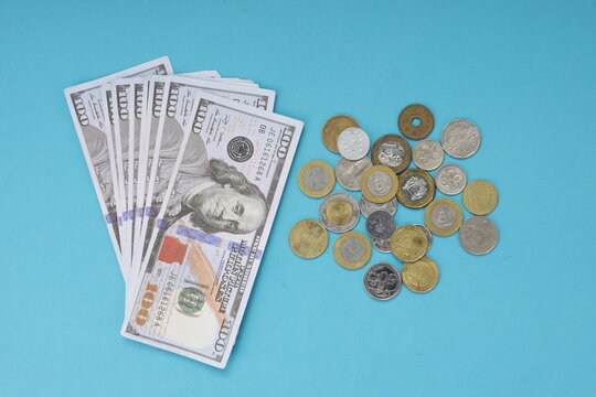 International Travel Budgeting Concept with Dollar Cash and Foreign Coins on Blue Background